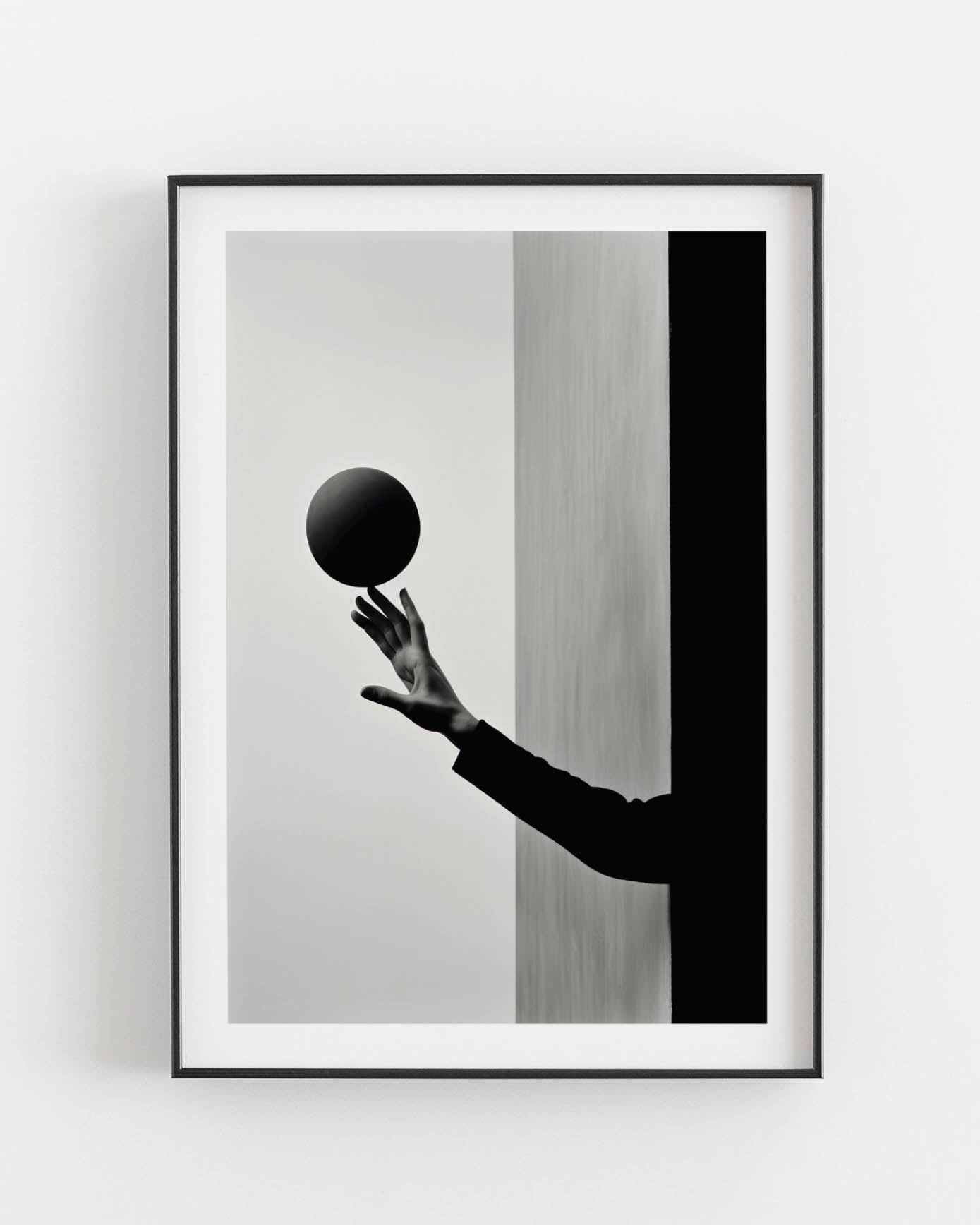 Black and white photograph of a hand holding a dark sphere, juxtaposed against contrasting vertical backgrounds.