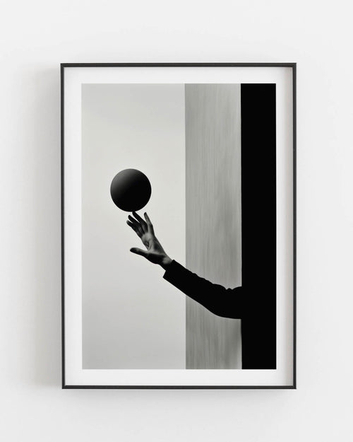 Black and white photograph of a hand holding a dark sphere, juxtaposed against contrasting vertical backgrounds.