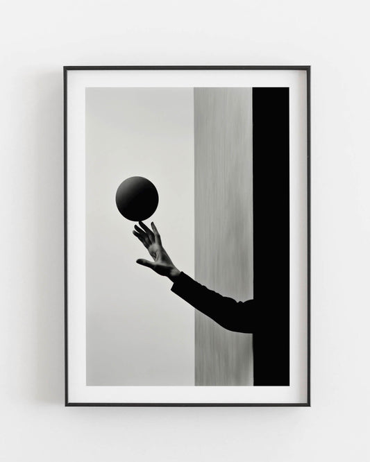 Black and white photograph of a hand holding a dark sphere, juxtaposed against contrasting vertical backgrounds.