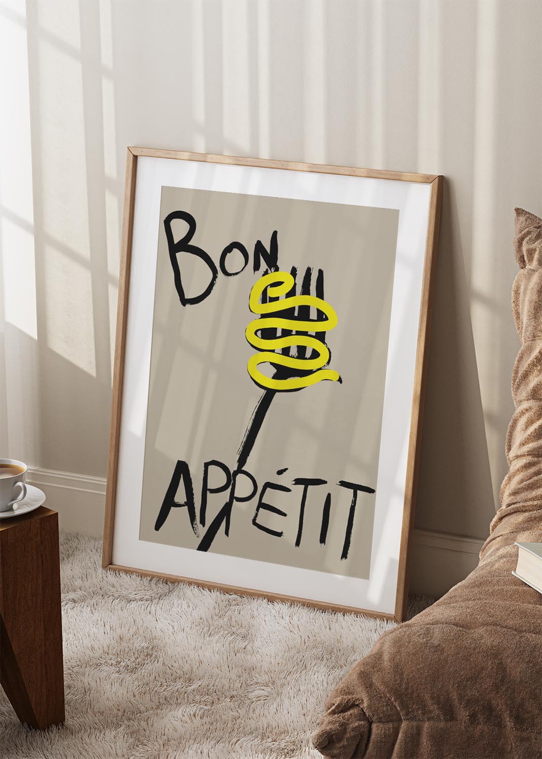 Poster artwork with “Bon Appétit” in bold black brush letters, a black fork, and a swirl of bright yellow spaghetti on a beige background.