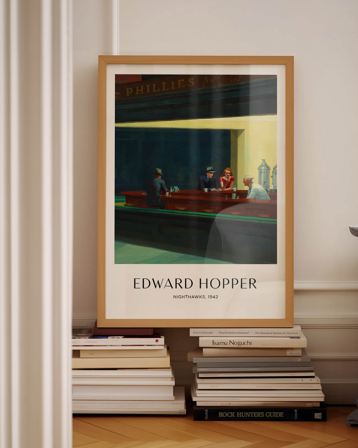 A poster of Edward Hopper's Nighthawks (1942), depicting a dimly lit diner at night with three patrons and a server, set against a dark, deserted urban backdrop. The scene is bathed in warm, moody light, evoking solitude and quiet introspection.