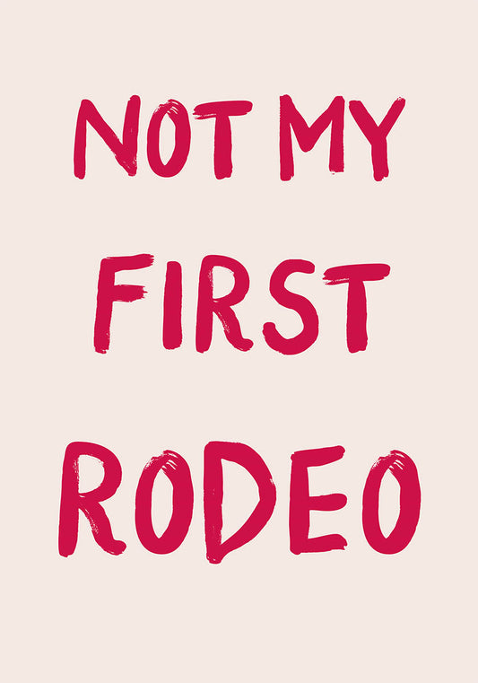 A trendy poster with the phrase "NOT MY FIRST RODEO" in bold red brush script font on a pastel pink background, conveying a sense of humor and confidence