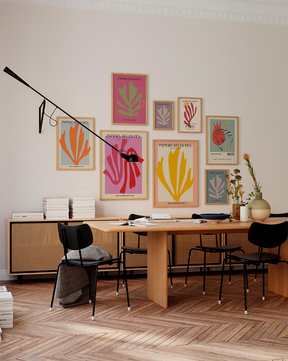 Interior design featuring a gallery wall of Matisse-inspired 'Papiers Découpés' posters in various colors displayed in a modern office space with a wooden desk, black chairs, and a mid-century sideboard.