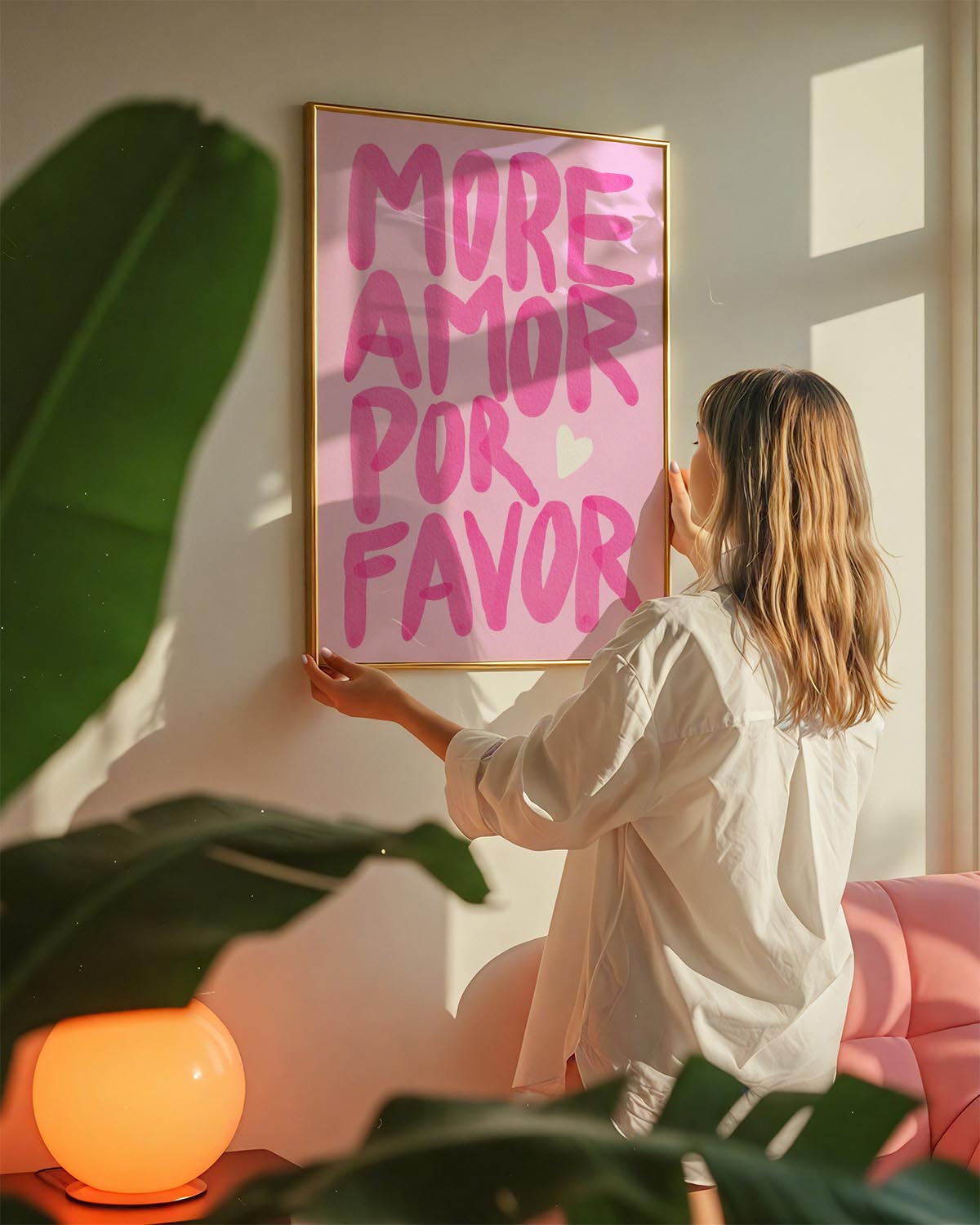Poster with the phrase “More Amor Por Favor” in bold pink hand-painted letters on a light pink background, with a small white heart.