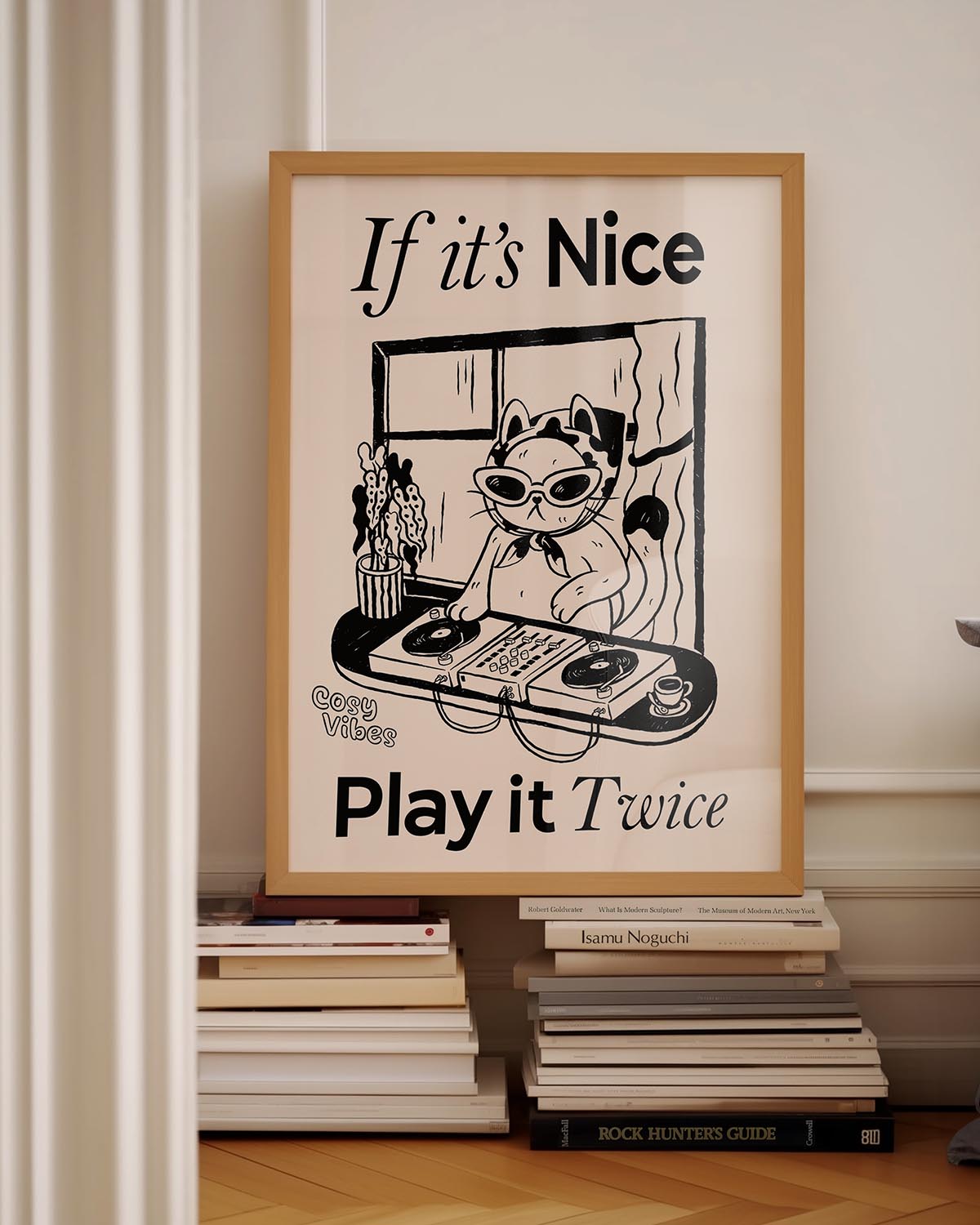 Illustrated poster of a cool cat DJ wearing sunglasses and a headscarf, spinning vinyl records on a turntable in front of a window. The text reads "If it’s Nice, Play it Twice" with "Cosy Vibes" written in the corner. The artwork is in a black-and-white, hand-drawn style.