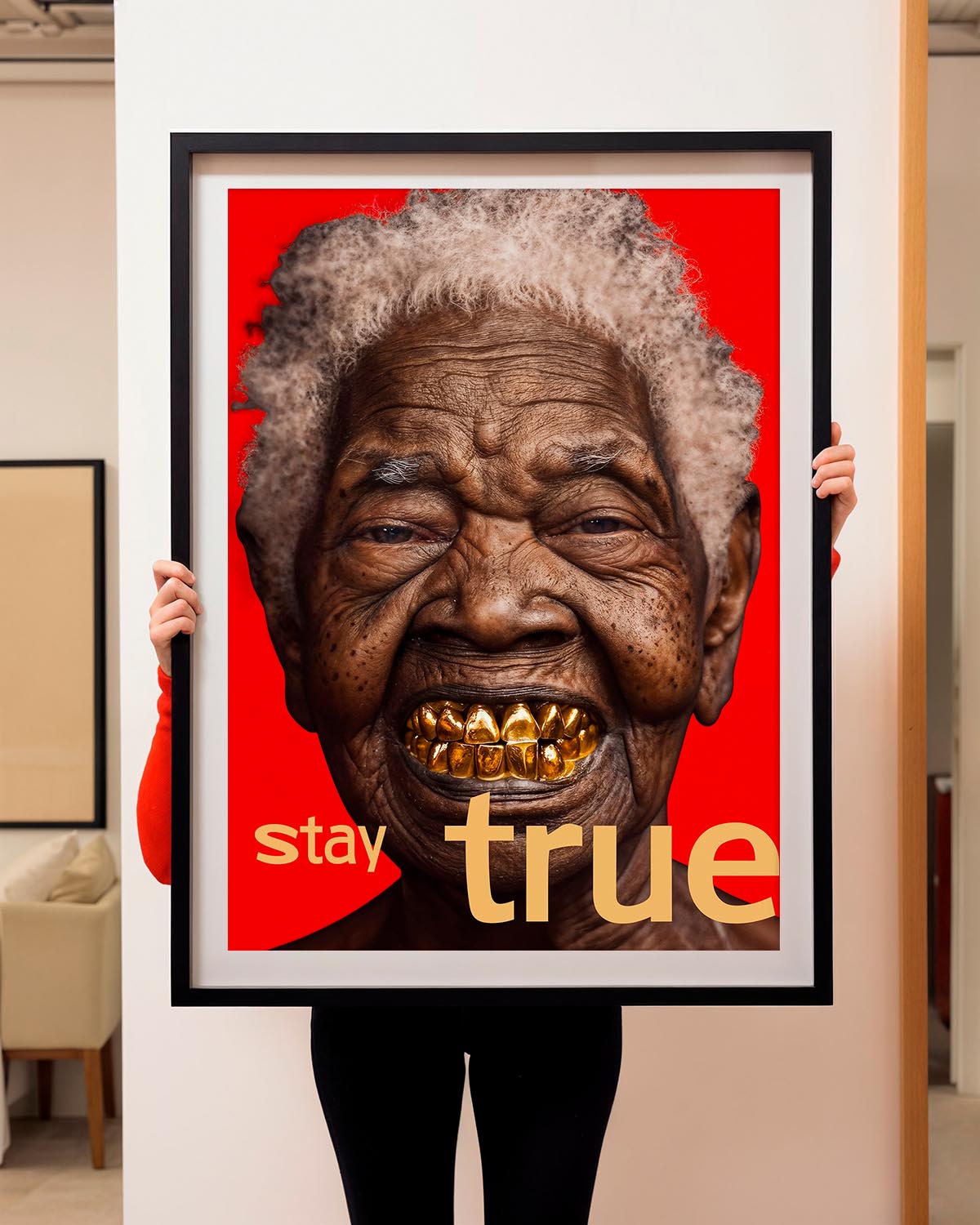  A close-up portrait of an elderly individual with a broad smile, revealing gold-plated teeth. Their skin is richly textured with deep wrinkles and they have a head of curly grey hair. The background is a vivid red with the words "stay true" in gold, lowercase font positioned at the bottom. The image conveys a message of authenticity and lived experience.